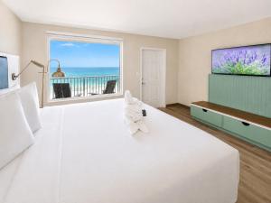 a large bedroom with a large bed with a television at Palm & Tide Beachfront Hotel in Panama City Beach +27 photos