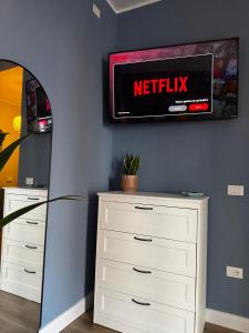 a television on a wall above a dresser with a mirror at Casa Agata in Chioggia