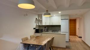 a kitchen with white cabinets and a table with chairs at BPirineos-Mulleres in Benasque