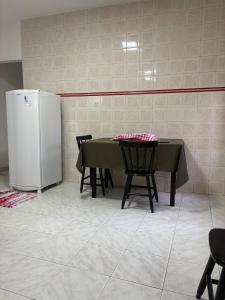 a kitchen with a table and a refrigerator at Excelente apartamento espaçoso com terraço in Macaé