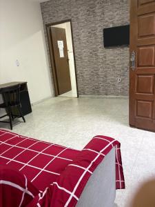a room with a bed with a table and a door at Excelente apartamento espaçoso com terraço in Macaé