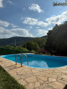 a blue swimming pool with mountains in the background at Vikendica Andrija Drina in Gvozdačko Polje