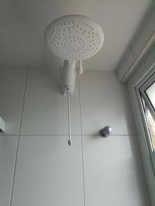 a ceiling light in a room with white tiles at Piscina aquecida e varanda, dois quartos com ar condicionado in Aracaju