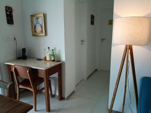 a room with a table with a lamp and a table with a chair at Piscina aquecida e varanda, dois quartos com ar condicionado in Aracaju