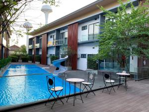 a swimming pool with tables and chairs next to a building at The RiverKwai Bridge Resort 2 in Ban Chuk Kum