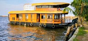 a yellow house boat parked in the water at Navora Houseboats in Alleppey
