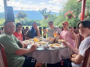 a group of people sitting around a table eating food at PROKLETIJE COTAGESEe in Plav