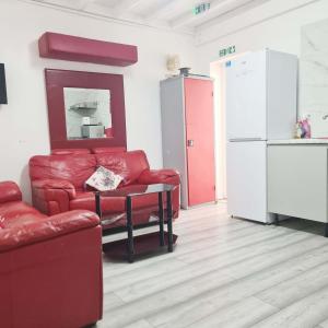 a living room with a couch and a table and a refrigerator at Park View in Goodmayes