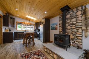 a kitchen with a stone fireplace and a stove at Rustic Old West Cabin 1 Block to Beach Accessible Private Yard in Sylvan Lake