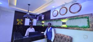 two men standing at a counter in a room with clocks at Kiarra Suites Owerri in Owerri