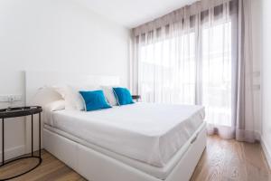 1 dormitorio blanco con 1 cama blanca grande con almohadas azules en Puerta del Sol, en Sevilla
