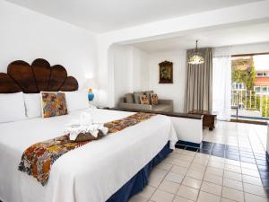 a bedroom with a large bed and a living room at Los Arcos Suites in Puerto Vallarta