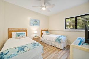 a bedroom with two beds and a flat screen tv at Makai Dream (Oceanfront) in Lihue +75 photos