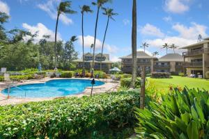 a resort with a swimming pool and palm trees at Makai Dream (Oceanfront) in Lihue