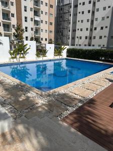 a large blue swimming pool with buildings in the background at The Liras Oasis in Santiago de los Caballeros