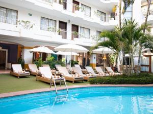 a hotel swimming pool with lounge chairs and umbrellas at Los Arcos Suites in Puerto Vallarta
