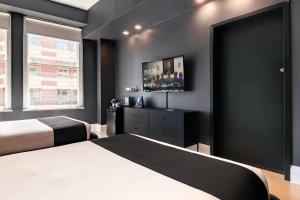 a bedroom with two beds and a flat screen tv at Madison Square Hotel Near NoMad in New York +39 photos