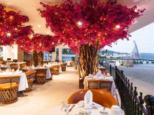 a restaurant with tables and trees with red flowers at Los Arcos Suites in Puerto Vallarta