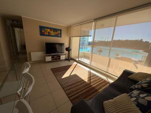 a living room with a couch and a television at Laguna Bahia Velero in Algarrobo