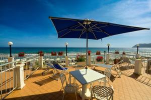 a patio with a table and chairs and the ocean at Hotel La Balnearia in Alassio