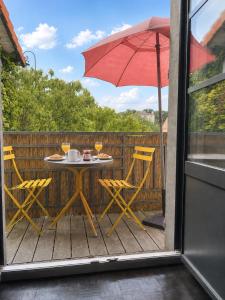 a table and chairs with an umbrella on a deck at Maisonnette Clisson quartier Trinité in Clisson