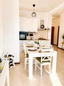 a white kitchen with a white table and chairs at Little house Lezzeno in Lezzeno