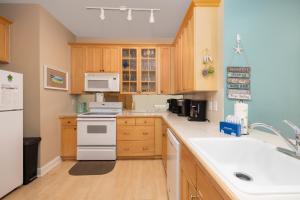 a kitchen with wooden cabinets and white appliances at Beachwalk Villas 22 in Folly Beach