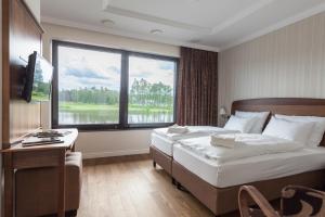 a bedroom with a bed and a desk and a large window at GolfBay Villa in Senica