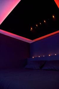 a dark room with a bed with red and purple lights at House-Evasion in Tuchan