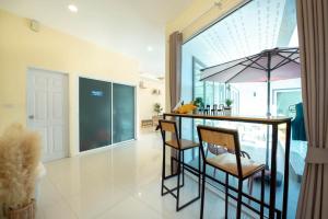 a kitchen with a bar with chairs and an umbrella at Scarlet Poolvilla Pattaya in Na Jomtien