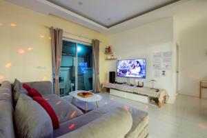 a living room with a couch and a television at Scarlet Poolvilla Pattaya in Na Jomtien