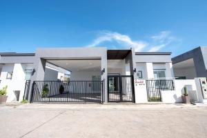 a white house with a gate in a driveway at Scarlet Poolvilla Pattaya in Na Jomtien