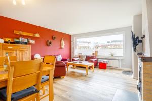 a living room with orange walls and a red couch at Bungalow Hohes Riff in Norddeich