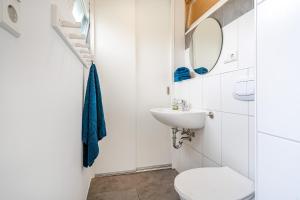 a white bathroom with a toilet and a sink at Bungalow Hohes Riff in Norddeich +13 photos