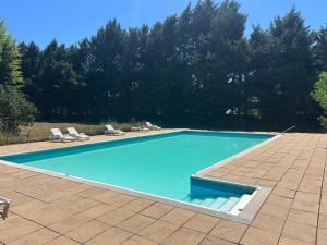 a swimming pool with blue water in a yard at ADONIS CHAMBRES D'HOTES in Saint-Germain-Laprade