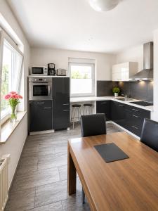 a kitchen with black cabinets and a wooden table at Ferienwohnung Sonnendeck einladend und freundlich in Laupheim