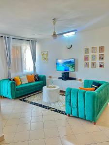 a living room with two green couches and a tv at tabby stays one bedroom with two beds bamburi in Mombasa