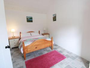 a bedroom with a bed and a pink rug at Historic Louisburgh Farm Cottage in Louisburgh
