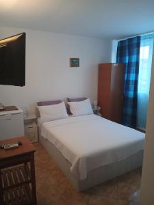 a bedroom with a large white bed and a television at casa andrei m in Eforie Sud