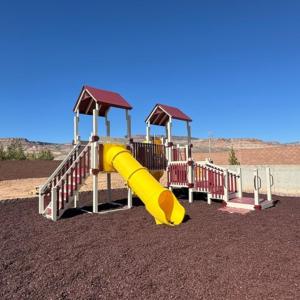 a playground with a yellow slide in the desert at Zion Vacation Cabins in Virgin