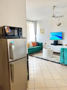 a kitchen with a refrigerator and a living room at tabby stays one bedroom with two beds bamburi in Mombasa