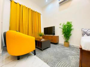 a room with a yellow curtain and a bed and a tv at Résidence moncloa in Brazzaville