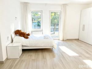 a white bedroom with a teddy bear on a bed at Casaxxvaprile in Turin