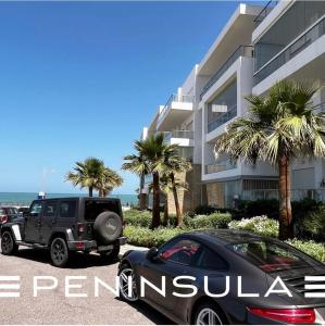 a jeep parked in front of a building with palm trees at Peninsula promenade in Tamaris