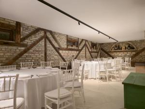 a room with white tables and chairs and a brick wall at Imanje Dorf in Ravno Selo