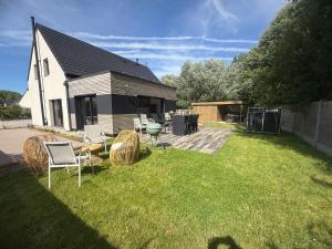 a backyard with chairs and a grill and a house at Villa Confidentielle Opale in Merlimont