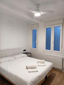 a white bedroom with two beds and a ceiling fan at MBE Bilbao Centro, 3Hab, 2 Baños, jacuzzi in Bilbao