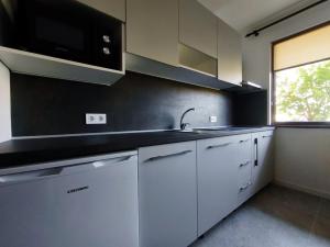 a kitchen with white cabinets and a sink and a window at Yanevi Apartments in Chernomorets