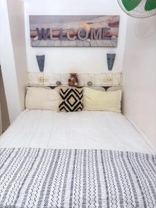 a bedroom with a white bed with a sign on the wall at Bungalow 2 chambres salon in Ngaring