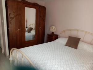 a bedroom with a white bed and a mirror at petite maison Bellevue in La Celle-sous-Gouzon
